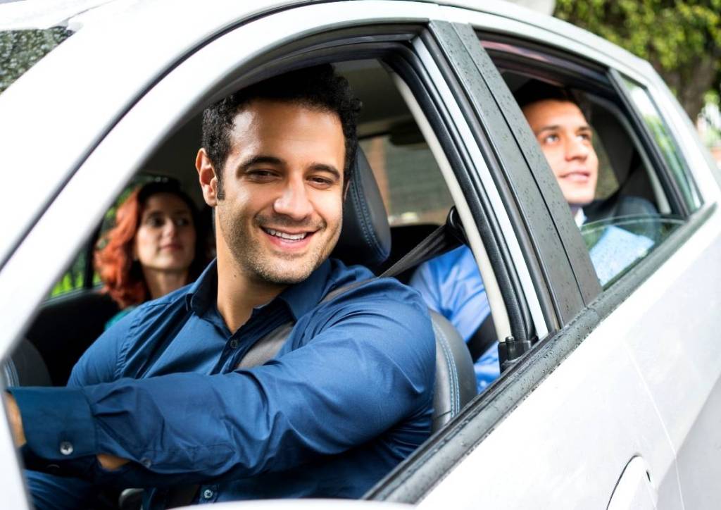 foto da janela de um carro e com o motorista sorrindo