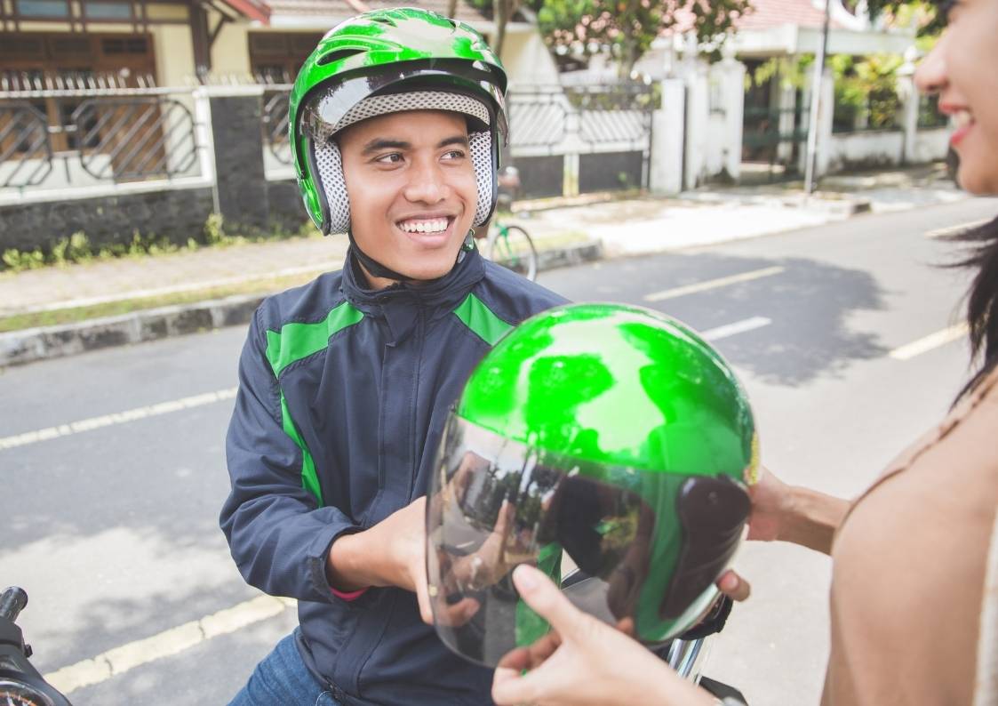 Mototaxista entregando capacete para passageira