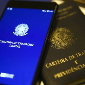 Aplicativo de Carteira de Trabalho Digital em um smartphone ao lado de uma Carteira de Trabalho física.