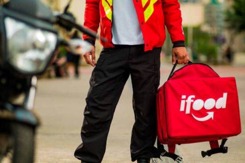 Entregador do iFood segurando a bag da moto.
