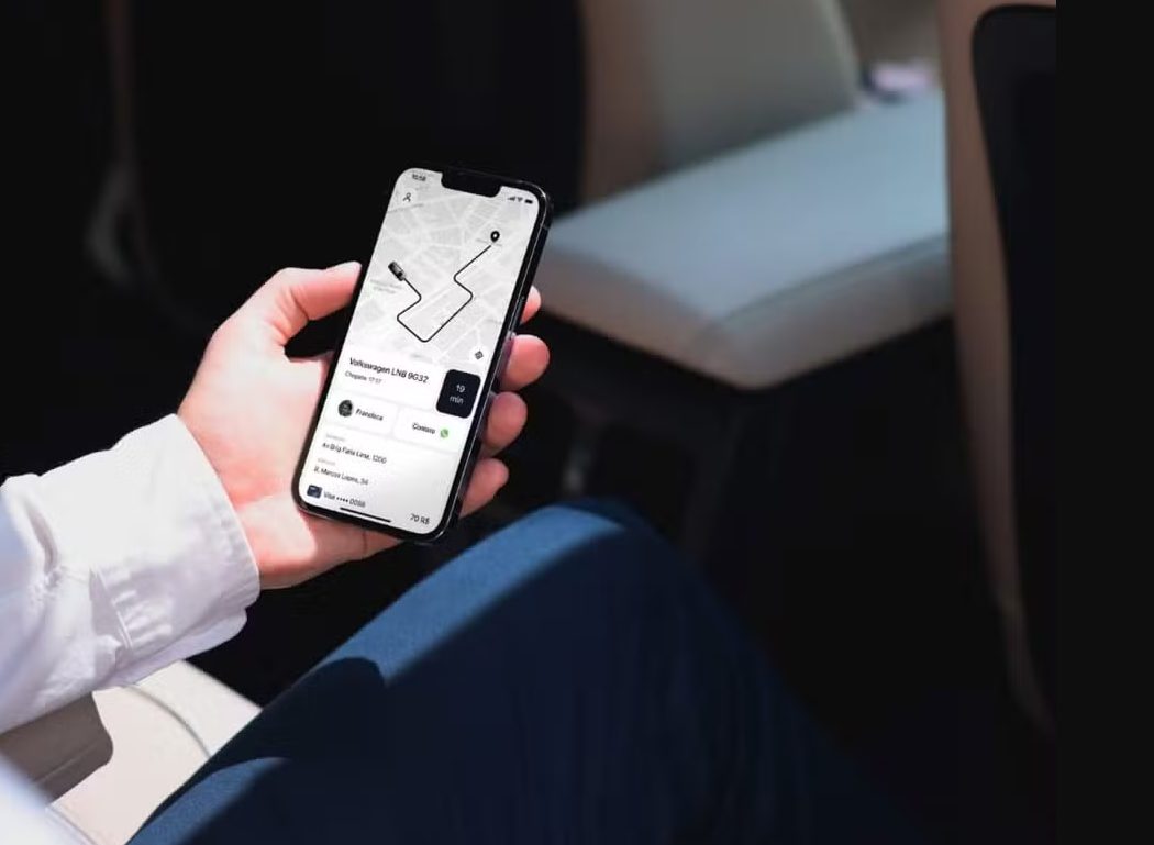 Mão de um homem branco segurando um celular com o app de mobilidade aberto.