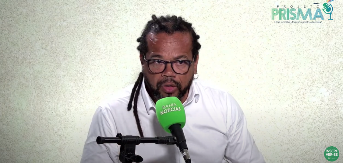 "Apresentador do Projeto Prisma do Bahia Notícias fala ao microfone em entrevista."