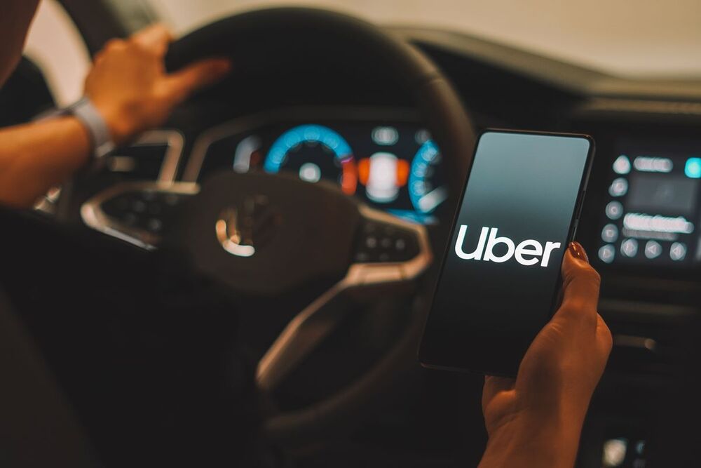 Motorista segurando smartphone com o aplicativo Uber aberto.