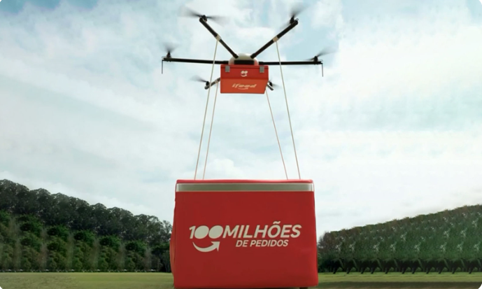 Drone de entrega carregando um pacote da iFood com o slogan "100 milhões de pedidos"