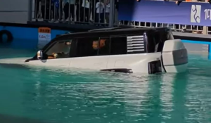 Um carro SUV parcialmente submerso em uma piscina de exibição, com a água cobrindo mais da metade do veículo.