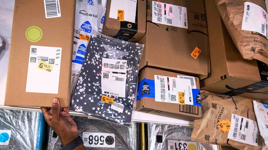 Várias encomendas embaladas da Amazon prontas para entrega, incluindo caixas e pacotes, em um centro de distribuição.