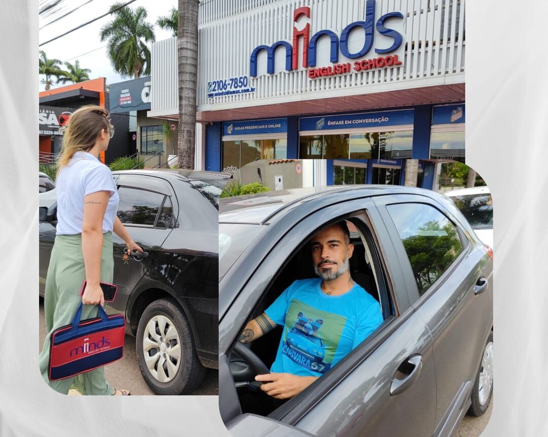 Mulher abrindo a porta de um carro preto com uma bolsa da Minds English School e homem sentado no carro usando uma camiseta azul estampada com capivara.