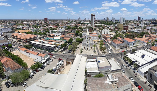 Vista panorâmica de Mossoró, Rio Grande do Norte, destacando construções históricas, ruas arborizadas e a Igreja Matriz de Santa Luzia ao centro, com a cidade ao fundo.