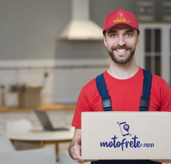 Entregador segurando uma caixa com o logotipo do MotoFrete.app, usando uniforme vermelho e boné com o nome da empresa.