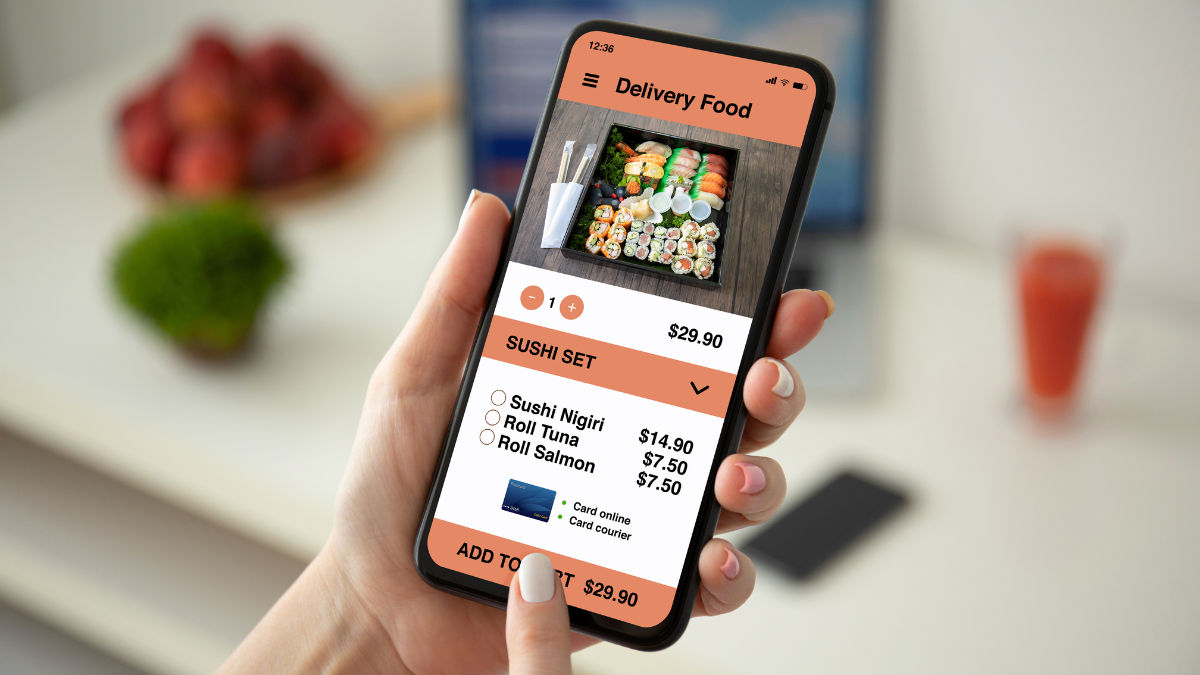 Pessoa segurando um celular exibindo a interface de um aplicativo de delivery de comida com opções de sushi para compra.