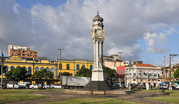 Relógio da Praça do Relógio, um monumento histórico no centro de Belém, com prédios coloridos ao fundo e céu parcialmente nublado.