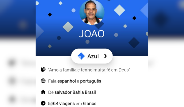 Captura de tela de um perfil em um aplicativo de transporte. A imagem mostra um motorista chamado João com um fundo azul decorado com formas geométricas. Abaixo da foto de perfil, há informações como idioma falado (espanhol e português), local de origem (Salvador, Bahia, Brasil), e o total de viagens realizadas (5.914 em 6 anos). Também há uma seção de elogios recebidos com diferentes ícones e números.