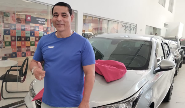 Homem de camiseta azul sorrindo e fazendo um gesto de positiv