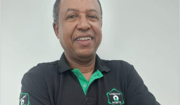 Homem sorridente vestindo camisa polo preta com detalhes verdes e o logotipo "Urbano Norte".