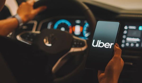 Motorista segurando smartphone com o aplicativo Uber aberto.