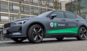 Carro elétrico da Dantaxi estacionado em uma rua urbana, com a identidade visual da empresa em destaque na lateral do veículo.
