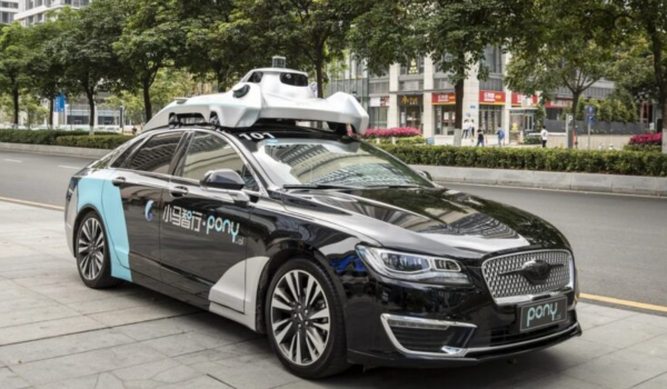 Carro autônomo da empresa Pony.ai estacionado na calçada de uma avenida urbana arborizada, equipado com sensores e câmeras no teto.