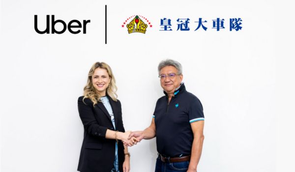 Margarita Peker, gerente geral da Uber Taiwan, e Wu Junde, presidente da Crown Taxi, apertando as mãos diante de um fundo branco com os logotipos da Uber e da Crown Taxi em chinês.