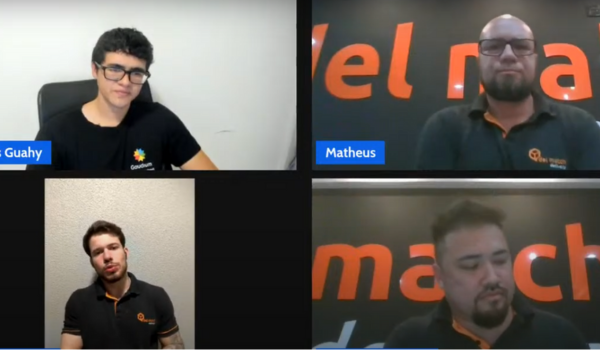Quatro homens participam de uma videoconferência. Dois usam camisetas com o logo da Golmatch, e um usa camiseta da Goahy. Todos estão em ambientes internos, cada um em seu respectivo quadro na tela.