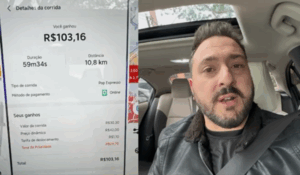Motorista de aplicativo dentro do carro mostrando na tela do celular um valor de R$103,16 recebido por uma corrida de 10,8 km e quase 1 hora de duração.