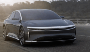 Carro elétrico de luxo Lucid Air estacionado em uma estrada, com design moderno, frente aerodinâmica e faróis finos de LED.