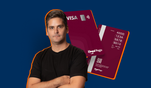 Homem de braços cruzados em frente a dois cartões vermelhos do iFood com bandeira Visa, com fundo azul escuro.
