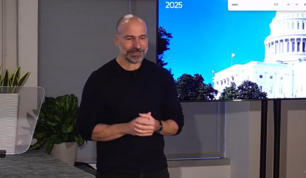 Homem fala durante apresentação em um evento, com uma tela exibindo o Capitólio dos Estados Unidos ao fundo.