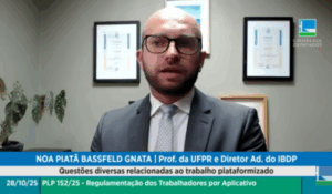 Homem de terno e gravata fala em videoconferência durante audiência pública sobre regulamentação de trabalhadores por aplicativo, com certificados emoldurados na parede ao fundo e logotipo da Câmara dos Deputados no canto da imagem.