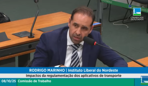 Homem de terno azul fala ao microfone durante audiência pública na Câmara dos Deputados sobre regulamentação dos aplicativos de transporte.