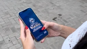 Pessoa segurando um smartphone com o aplicativo de corridas Giro Patos aberto na tela.
