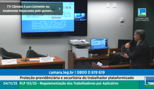 Homem em pé, segurando um microfone, apresenta um slide projetado em tela durante audiência pública na Câmara dos Deputados sobre a proteção previdenciária e securitária do trabalhador plataformizado.