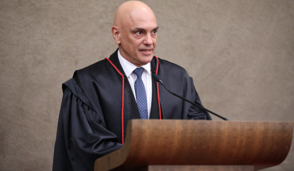 Quatro homens vestidos de terno posam em um palco ao ar livre com a inscrição “COP30 Local Leaders Forum”, tendo ao fundo um cenário arborizado e ensolarado.