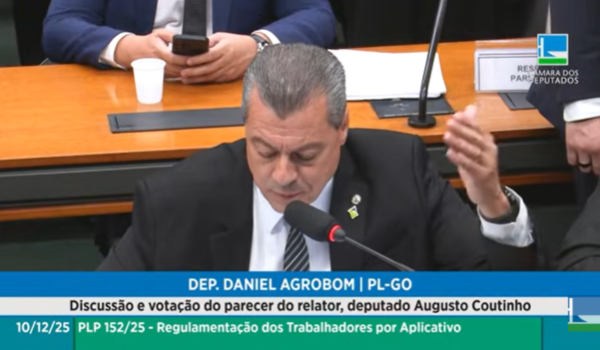 Deputado Daniel Agrobom fala ao microfone em comissão da Câmara, com identificação na tela e pauta sobre regulamentação de trabalhadores por aplicativo.