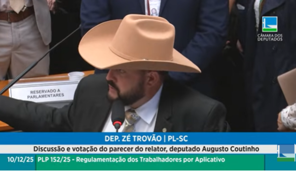 Homem de terno e chapéu grande de cowboy fala ao microfone em comissão da Câmara, com banner na tela sobre regulamentação de trabalhadores por aplicativo.