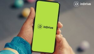 Pessoa segura um celular com a tela exibindo o logotipo da plataforma inDrive sobre fundo verde.