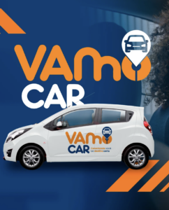 Carro branco com logotipo Vamo Car adesivado na lateral, sobre fundo azul com elementos gráficos em laranja e ícone de carro com pino de localização.
