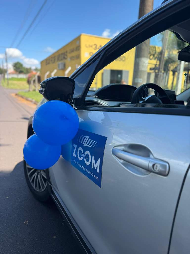 Carro com adesivo do aplicativo Zoom Passageiro estacionado em rua de cidade do interior