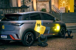 Carro elétrico da 99 estacionado em frente a prédio histórico com iluminação decorativa.