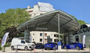 Posto de abastecimento de hidrogênio HYSETCO com cobertura moderna, carros e van estacionados na área externa