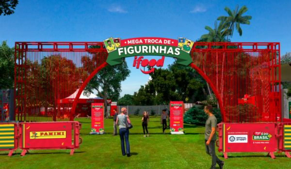 Entrada de evento promocional “Mega Troca de Figurinhas iFood” com estrutura vermelha montada em área gramada e pessoas circulando no local.