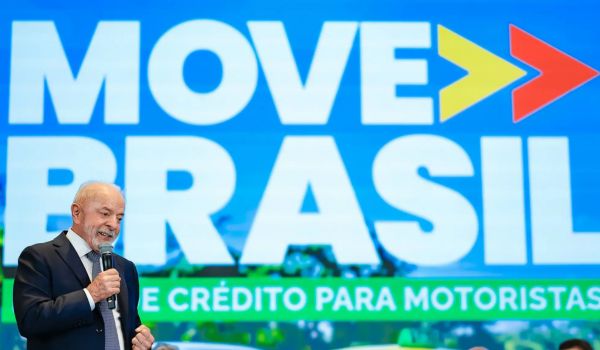 Presidente Lula discursando em evento do programa Move Brasil, com painel azul ao fundo e slogan sobre crédito para motoristas.