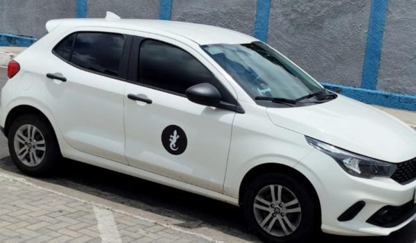 Carro branco da LagMob estacionado em vaga pavimentada, visto em perspectiva lateral.