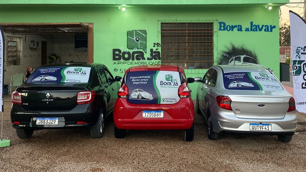 Três carros com publicidade da Bora Já estacionados diante de uma fachada verde identificada com a marca.