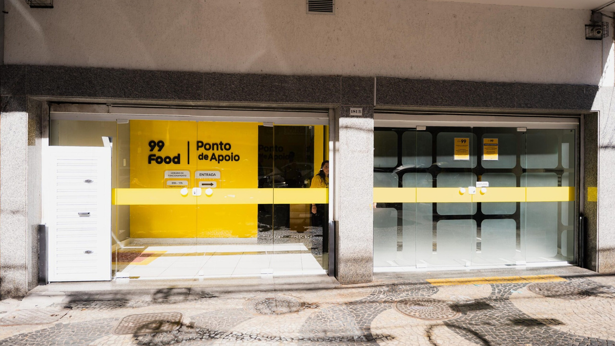 Fachada de um Ponto de Apoio da 99Food, com portas de vidro e identidade visual amarela.