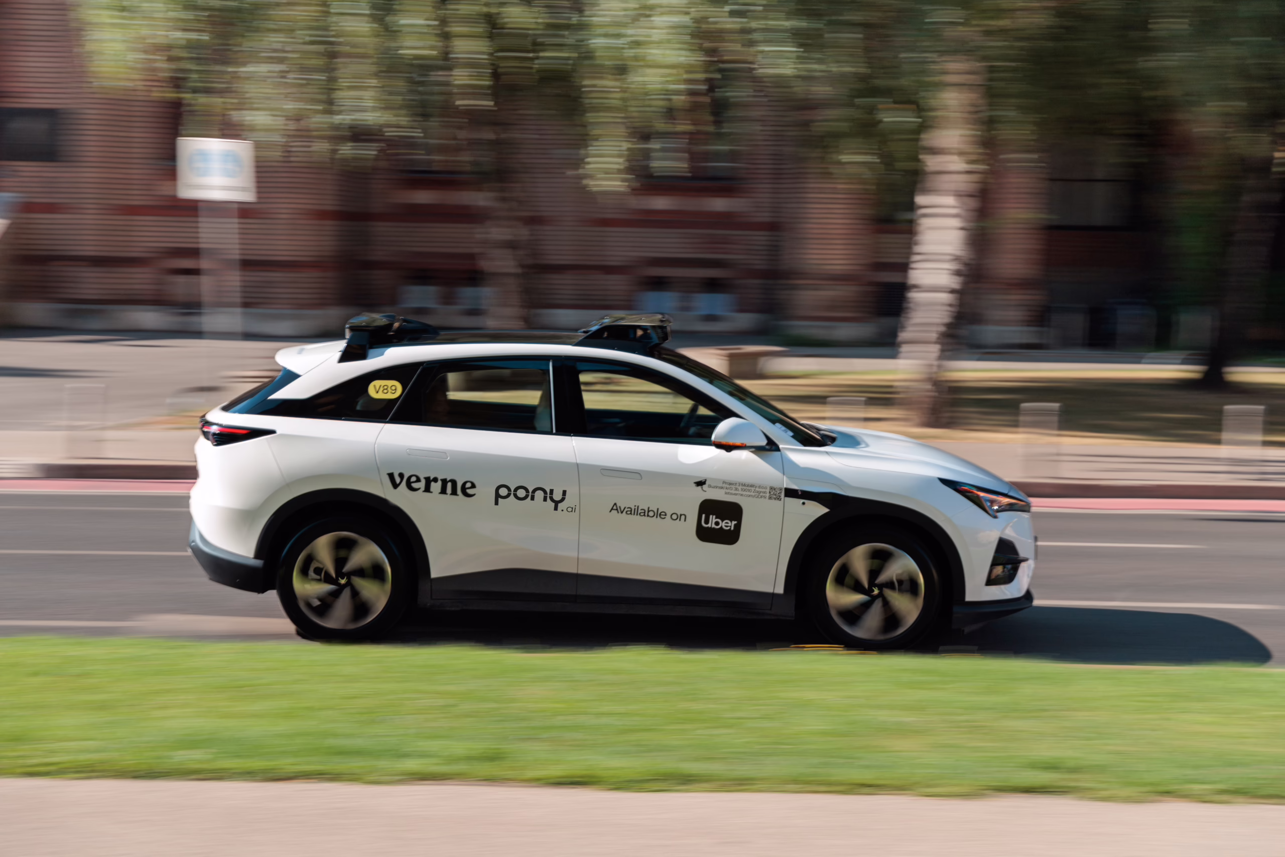 Veículo autônomo branco da Verne, equipado com tecnologia da Pony.ai e integrado à Uber, circula por uma via urbana.