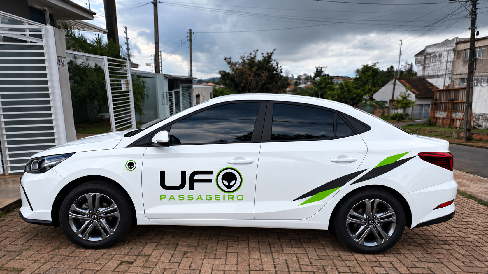 Carro branco com a identificação “UFO Passageiro” estacionado em uma rua residencial, sob céu nublado.